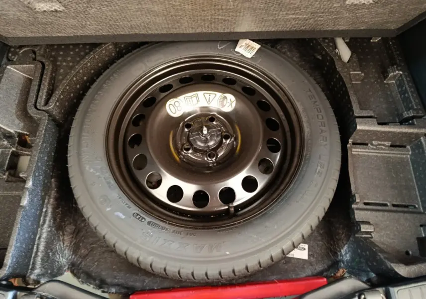 Vue plongeante sur la roue de secours noire logée dans le coffre du Ford Kuga bleu 2024 St Line.