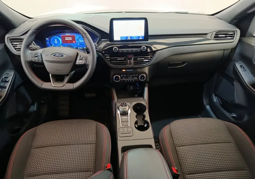 Intérieur du Ford Kuga 2024 St Line, vue frontale du poste de conduite avec écran tactile et volant multifonctions.