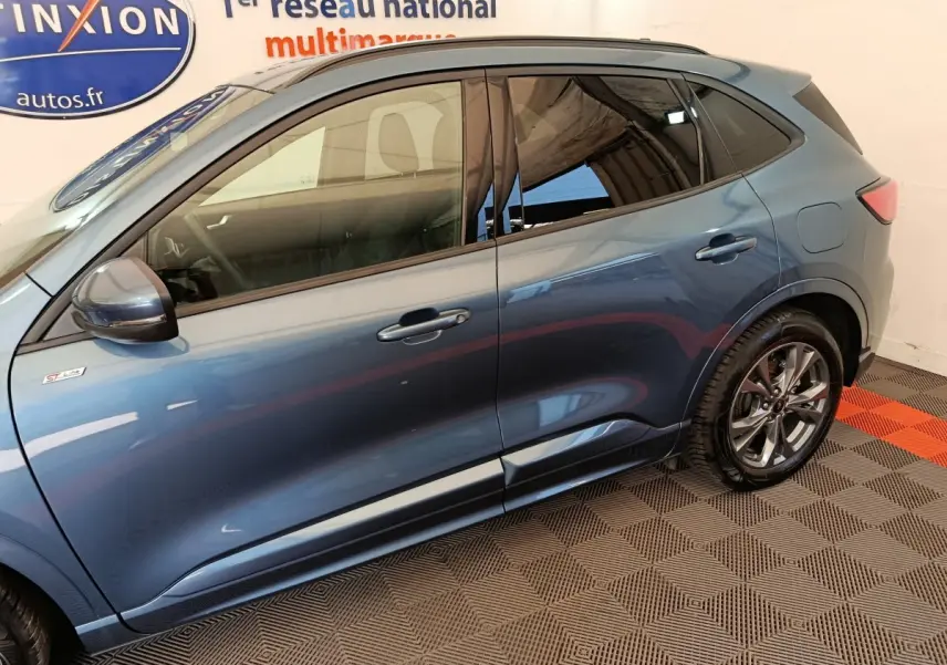 Profil côté gauche du Ford Kuga 2024 bleu, finition St Line avec jantes alliage et rétroviseurs assortis.