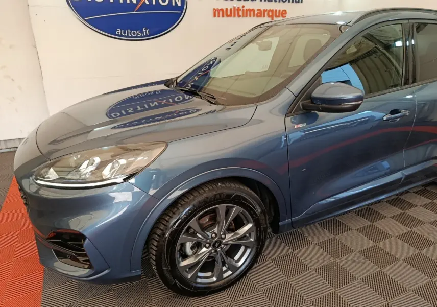 Vue 3/4 avant gauche d'un Ford Kuga bleu 2024 avec jantes alliage et badge St Line sur aile avant.