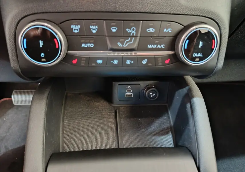 Vue rapprochée du panneau de commande de climatisation bicolore et ports USB du Ford Kuga 2024 intérieur noir.