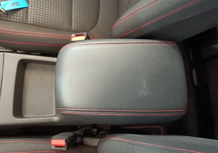 Gros plan sur l'accoudoir central noir avec surpiqûres rouges du Ford Kuga bleu 2024 version St Line.