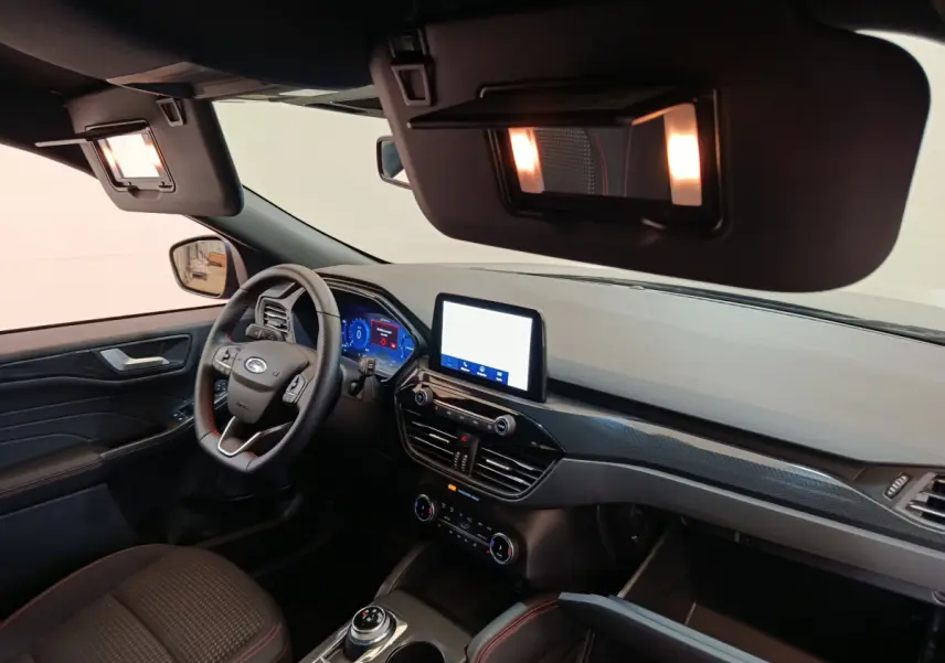Intérieur avant du Ford Kuga 2024 bleu, tableau de bord moderne avec écran tactile et volant multifonctions cuir noir.