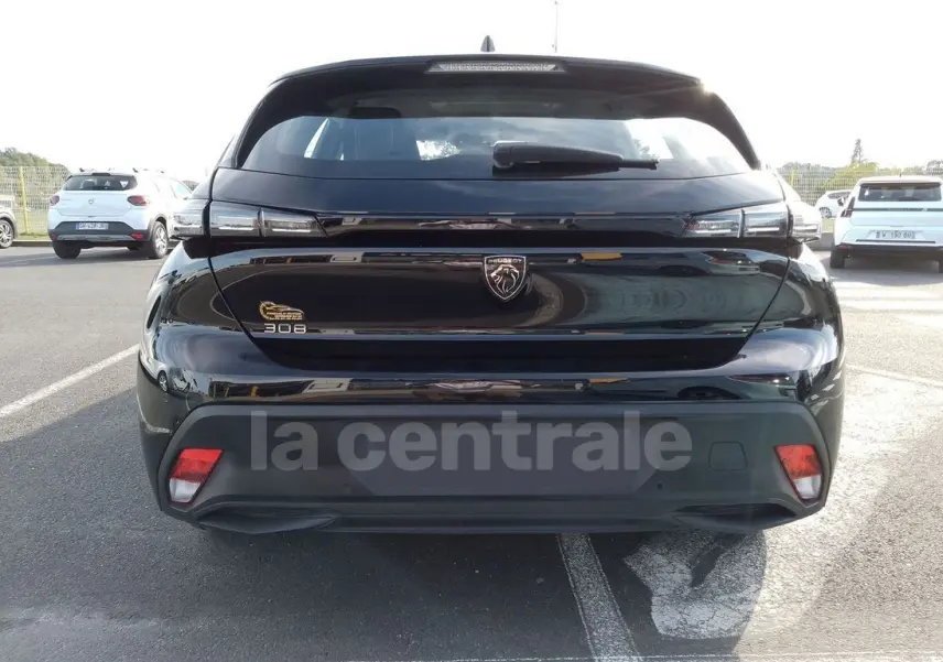 Vue arrière d'une Peugeot 308 noire 2022 avec logo lion et feux arrière étirés, stationnée en extérieur.
