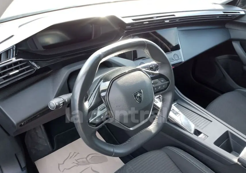 Vue intérieure du poste de conduite de la Peugeot 308 noire, avec volant cuir et tableau de bord moderne en 2022.