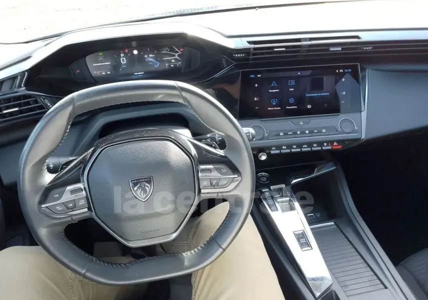 Vue intérieure centrée sur le volant cuir et le tableau de bord numérique de la Peugeot 308 noire de 2022.