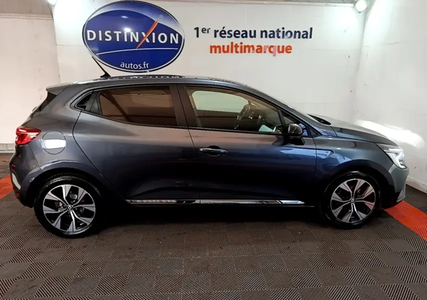 Profil droit d'une Renault Clio Evolution SCe 65 gris foncé 2022 avec jantes alliage et vitres teintées en intérieur showroom.