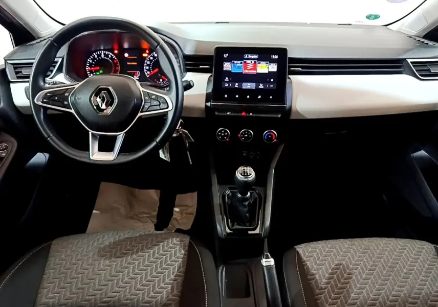 Vue intérieure avant de la Renault Clio gris foncé 2022, volant cuir, tableau de bord avec écran tactile central et boîte manuelle.