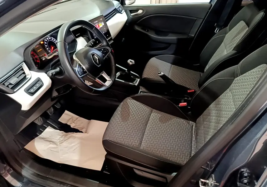 Vue intérieure côté conducteur de la Renault Clio gris foncé 2022, volant cuir, tableau de bord avec écran tactile.