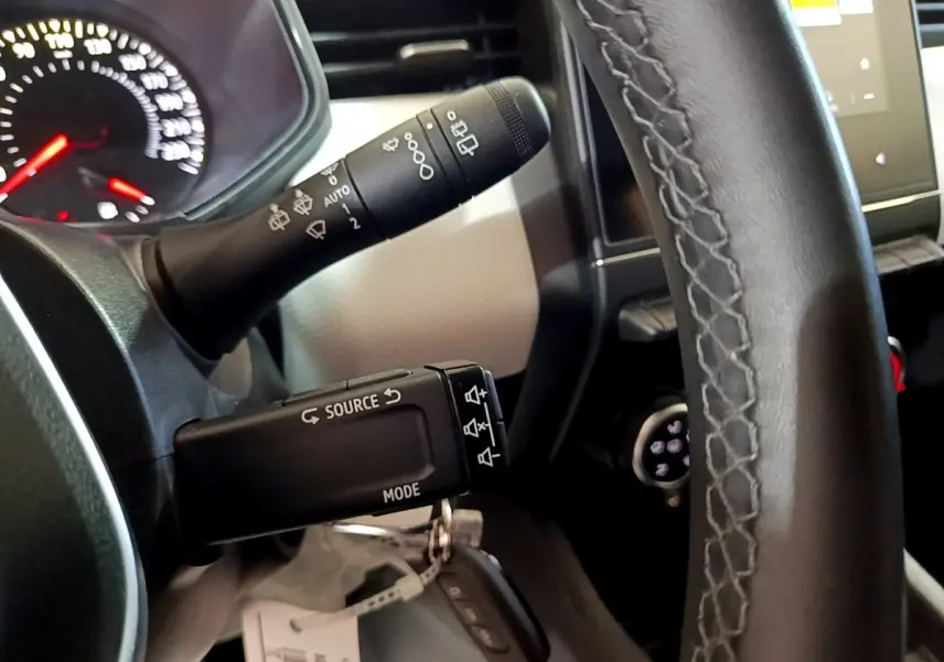 Gros plan sur la commande multifonction noire à gauche du volant en cuir noir de la Renault Clio gris foncé 2022.