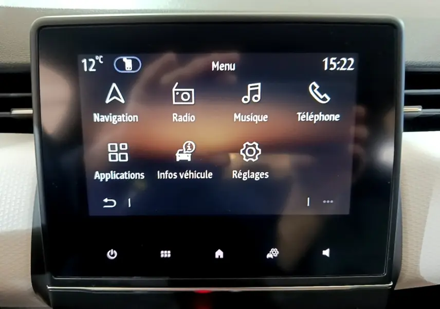 Écran tactile central de la Renault Clio gris foncé, affichant le menu principal avec navigation et réglages.