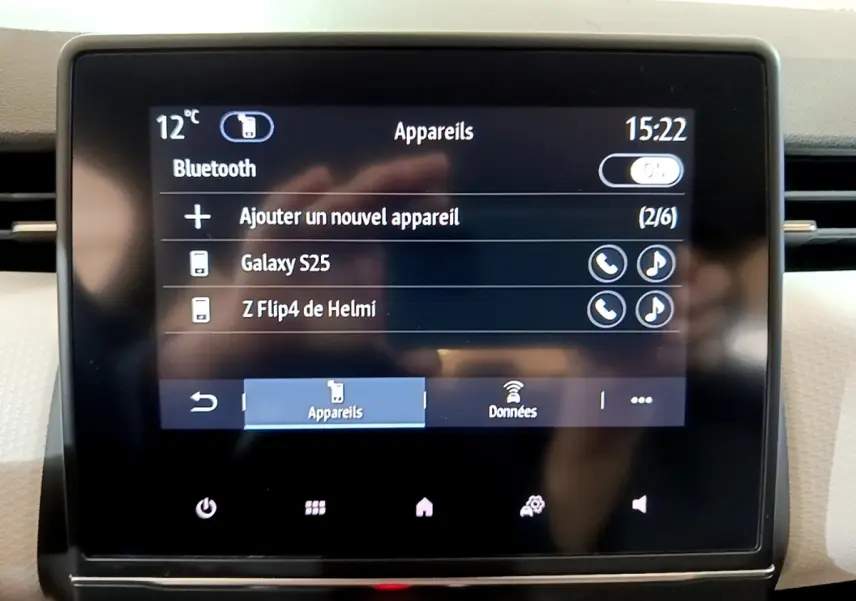 Écran tactile central de la Renault Clio gris foncé, affichant la connexion Bluetooth avec appareils listés.