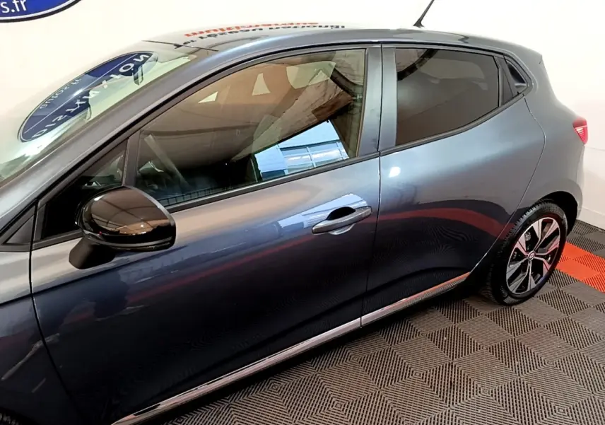 Vue latérale droite d'une Renault Clio gris foncé 2022 avec rétroviseur noir brillant et jantes alliage distinctives.