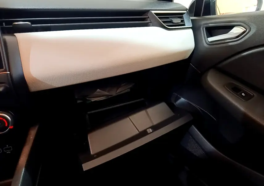Intérieur de la Renault Clio Evolution SCe 65 2022, vue côté passager sur la boîte à gants ouverte et tableau de bord gris clair.