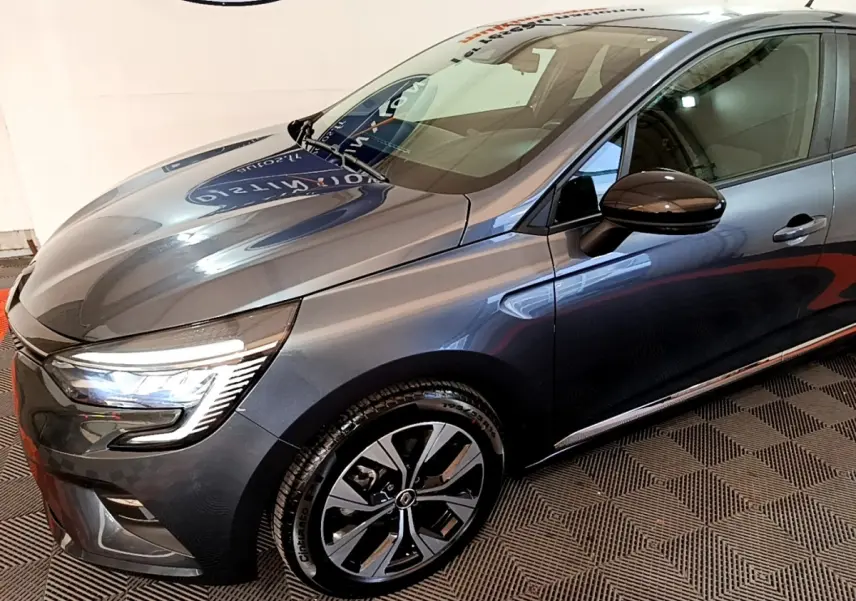 Vue 3/4 avant droit d'une Renault Clio Evolution gris foncé avec phares LED et jantes alliage distinctives.