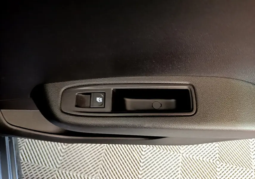 Gros plan sur la commande de lève-vitre électrique côté conducteur de la Renault Clio gris foncé Evolution SCe 65 2022.