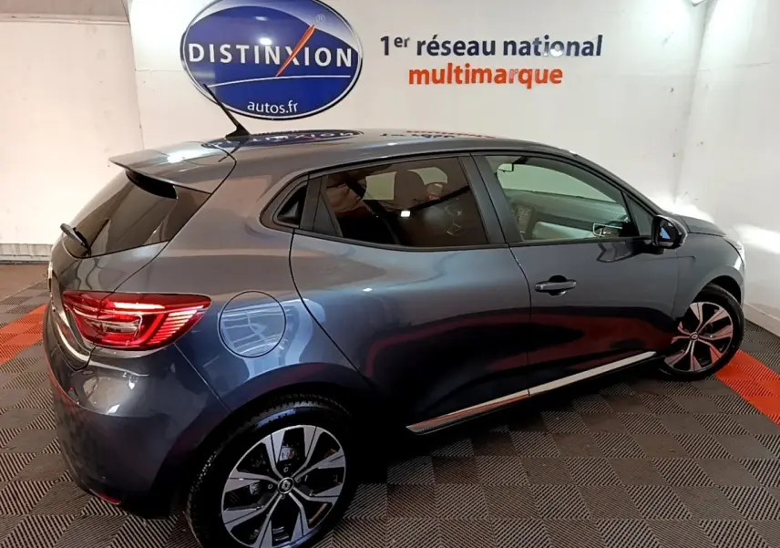 Vue 3/4 arrière droite d'une Renault Clio Evolution SCe 65 gris foncé avec jantes alliage et feux arrière LED allumés.