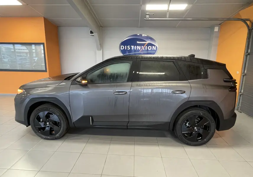 Coffre ouvert d'une Citroën C5 Aircross hybride gris platinium, avec sac noir posé au centre du coffre vide.