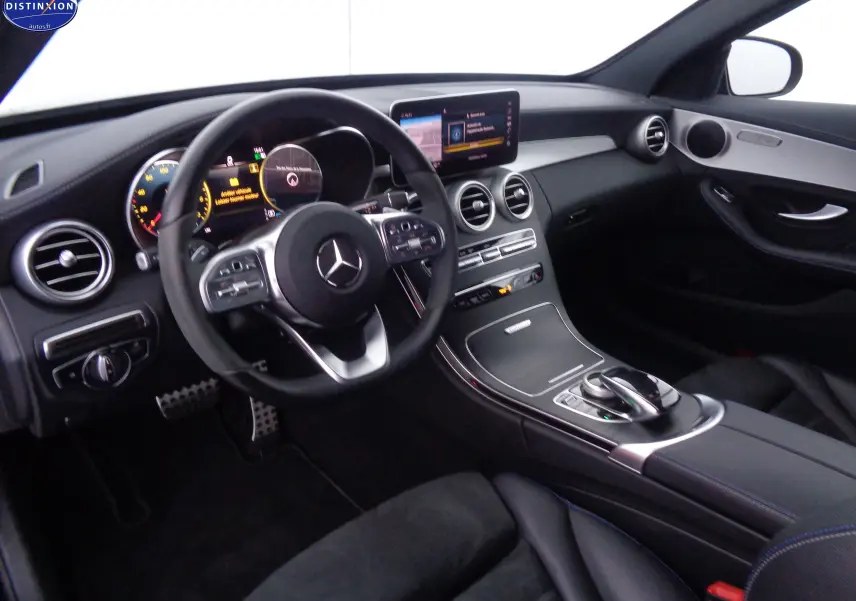 Vue intérieure côté conducteur d'une Mercedes Classe C Break 220D AMG Line 2021 avec tableau de bord noir et écran central.