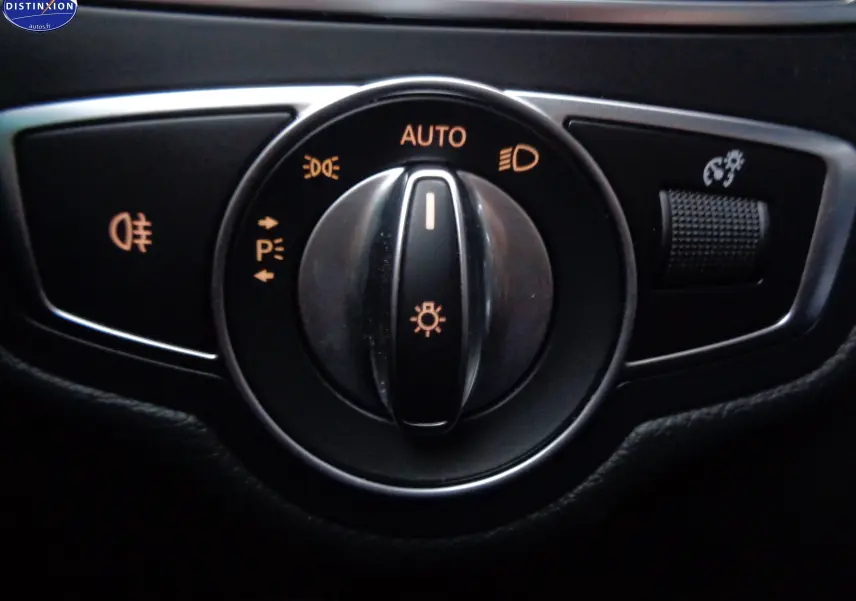 Gros plan sur la molette de réglage des phares avec fonction automatique, dans une Mercedes Classe C Break noire.