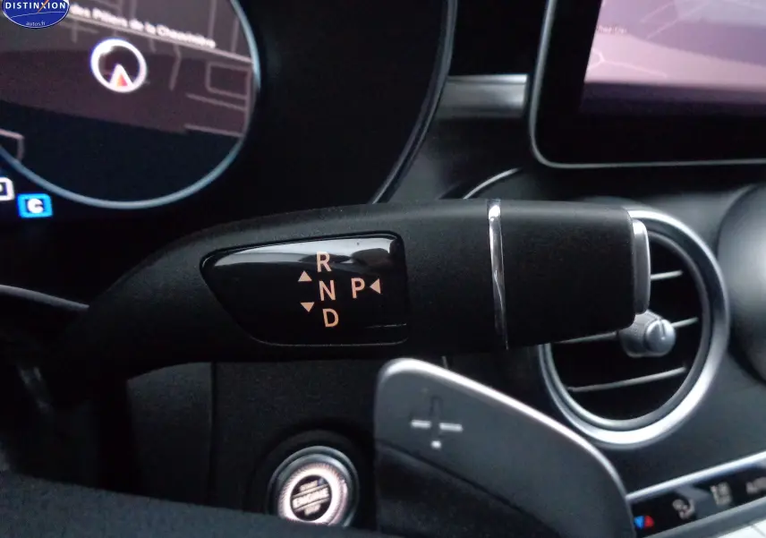 Gros plan sur la commande de boîte automatique à levier droit dans l'habitacle noir d'une Mercedes Classe C Break 220D AMG Line.