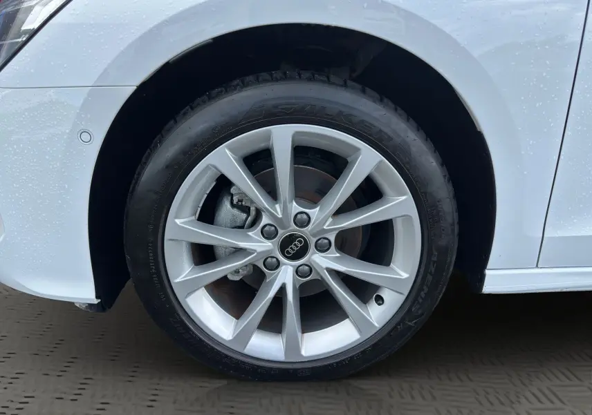 Gros plan sur la roue avant droite d'une Audi A3 Sportback blanche Arkona avec jante alliage léger à 10 branches.