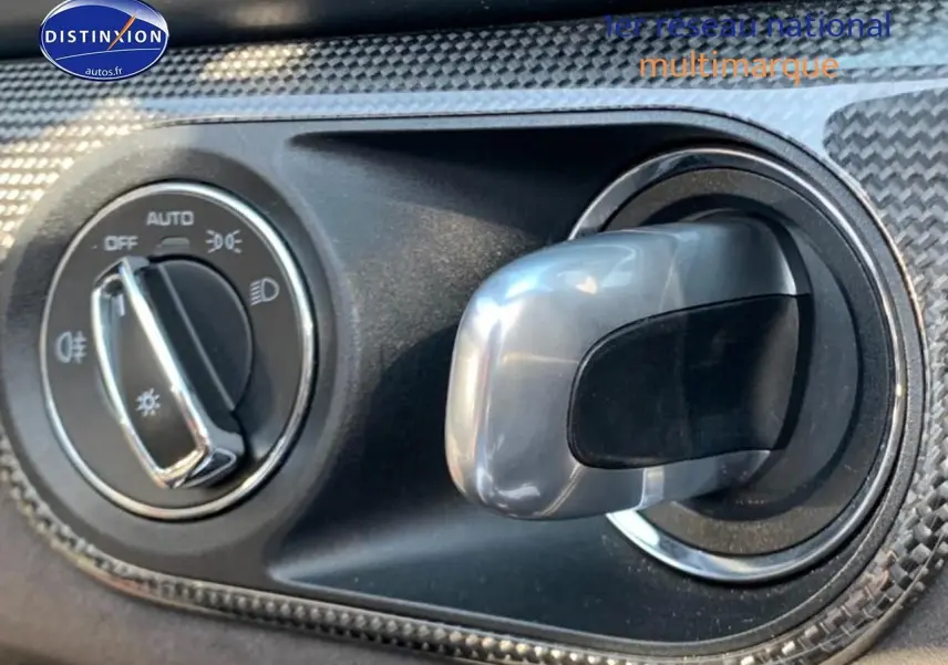 Gros plan sur la commande des phares et l'aération avec finition carbone dans l'habitacle noir de la Porsche Boxster rouge.