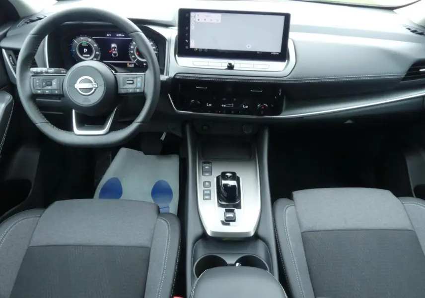 Intérieur avant du Nissan Qashqai 2025 avec tableau de bord numérique et console centrale moderne en gris et noir.