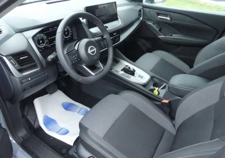 Intérieur avant droit du Nissan Qashqai 1.5 e-Power 2025 avec sellerie mixte gris et console centrale moderne.