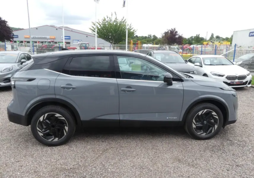 Profil côté gauche du Nissan Qashqai 2025 gris métallisé bi-ton avec toit noir et jantes alliage noires.