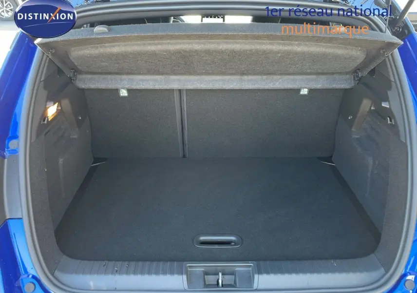 Coffre ouvert vu de l'arrière d'un Renault Captur bleu iron metal avec toit noir, montrant l'espace de chargement vide.