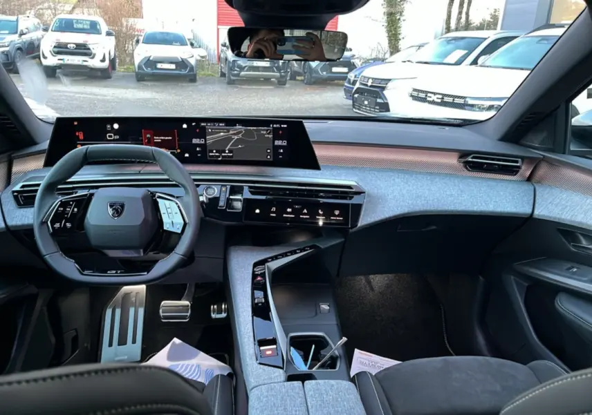Vue intérieure avant du Peugeot 5008 Hybrid 145 GT Alcantara 2025, tableau de bord moderne avec écran large et volant cuir multifonctions.