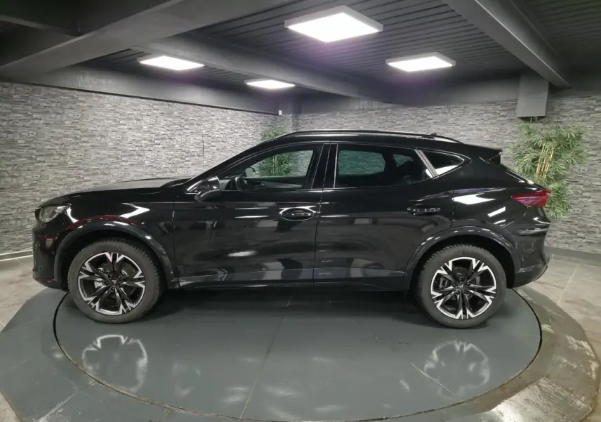 Profil côté gauche du CUPRA Formentor noir avec jantes alliage 18'' usinées dans un showroom intérieur.