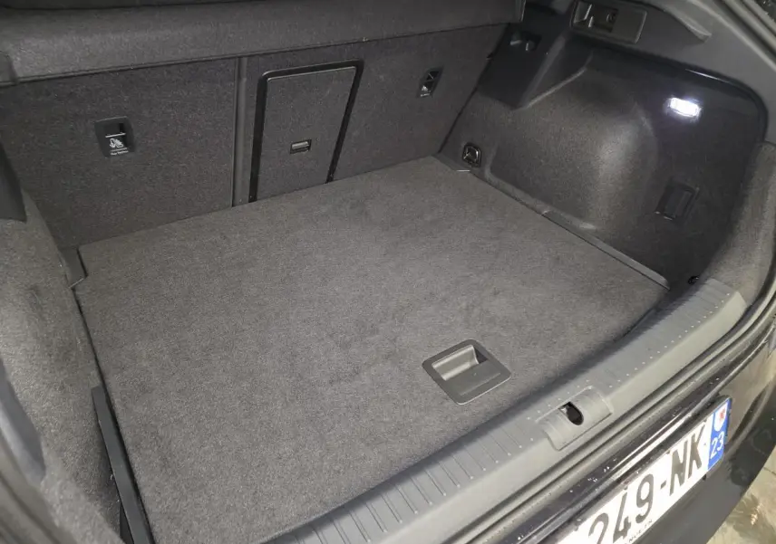 Coffre ouvert vu de l'arrière d'un CUPRA Formentor noir, avec tapis de sol gris et éclairage intérieur.