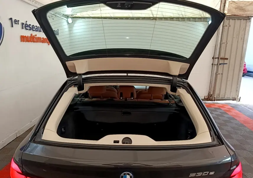 Vue arrière d’une BMW Série 5 Touring 530e gris clair avec coffre ouvert et intérieur visible en beige.