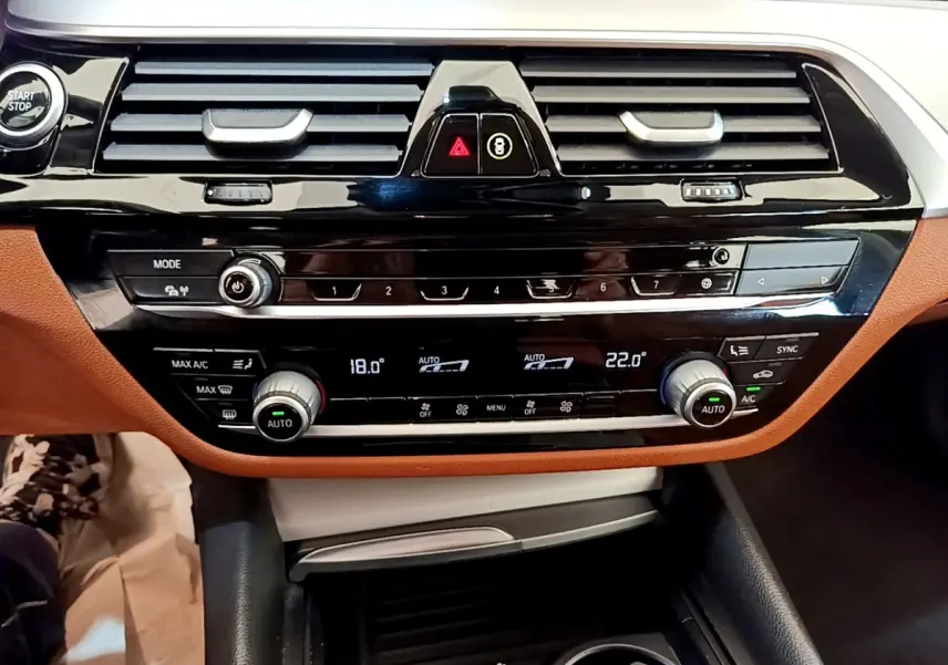 Vue rapprochée du tableau de bord noir et brun de la BMW Série 5 Touring 530e avec commandes climatisation digitales.