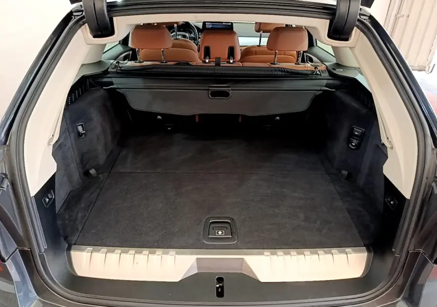 Vue arrière du coffre spacieux d'une BMW Série 5 Touring 530e gris clair avec sièges arrière en cuir marron.