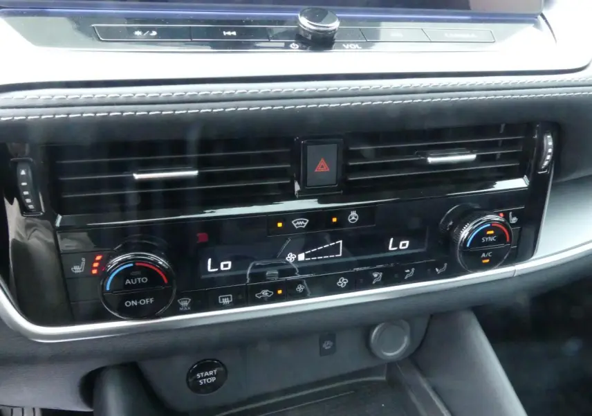 Détail de la console centrale noire brillante du Nissan Qashqai 1.5 e-Power 2025 avec commandes climatisation et bouton Start/Stop.