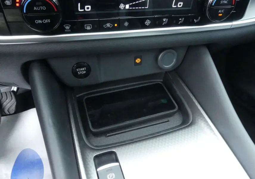 Vue rapprochée de la console centrale du Nissan Qashqai 2025 gris métallisé avec chargeur à induction et bouton Start/Stop.