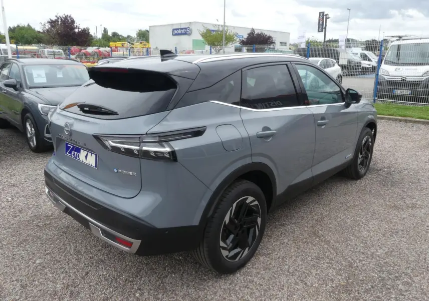Vue 3/4 arrière droite du Nissan Qashqai gris métallisé avec toit noir et jantes alliage au design moderne.