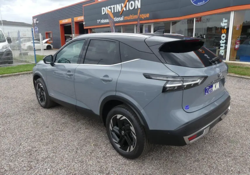 Nissan Qashqai 2025 gris métallisé bi-ton, vue 3/4 arrière côté gauche avec toit noir panoramique.