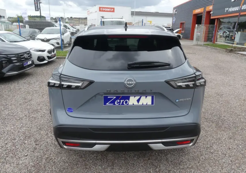 Vue arrière d'un Nissan Qashqai gris métallisé avec feux LED et badge e-Power sur un parking extérieur.