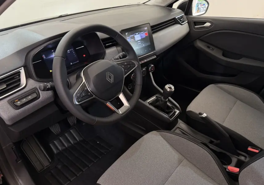 Intérieur de la Renault Clio Evolution Blue dCi 100 2025, vue côté conducteur, volant cuir et écran tactile central visible.