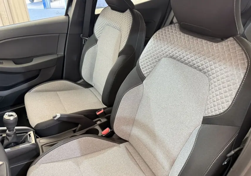 Gros plan sur les sièges avant gris et noirs de la Renault Clio Evolution Blue dCi 100 2025 avec levier de vitesse manuel.