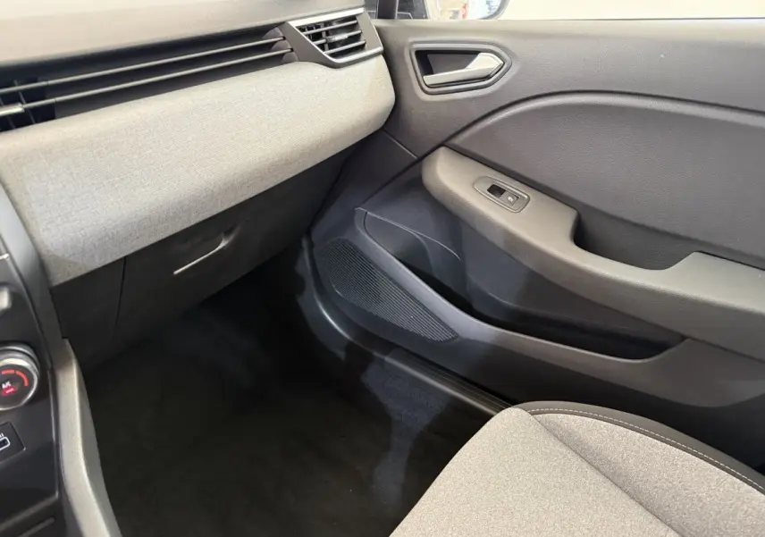 Intérieur côté passager de la Renault Clio noir 2025, montrant la porte et la partie inférieure du tableau de bord gris clair.