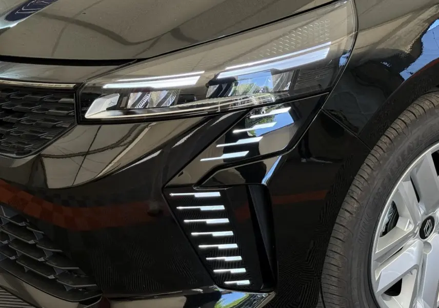 Gros plan sur le phare avant droit et la roue d’une Renault Clio noire 2025 avec feux LED distinctifs.