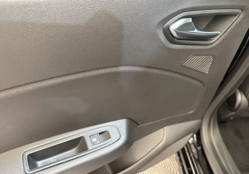 Gros plan sur la porte avant gauche de la Renault Clio noire 2025, montrant la poignée et la commande de fenêtre électrique.