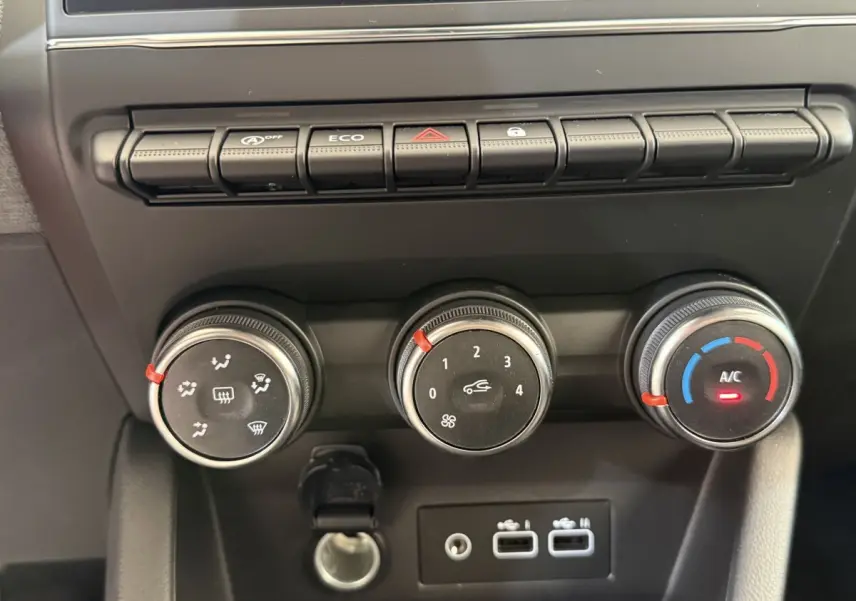 Gros plan sur les commandes de climatisation et les ports USB du tableau de bord de la Renault Clio noire Evolution 2025.