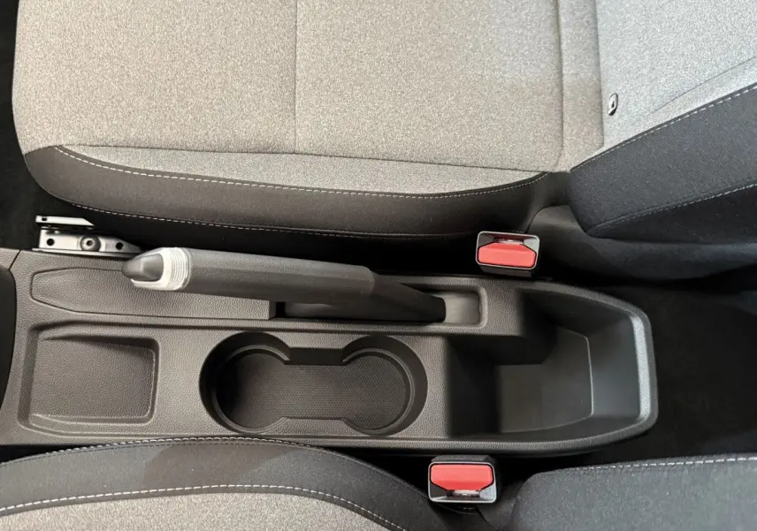 Vue plongeante sur la console centrale noire avec frein à main manuel et sièges tissu gris de la Renault Clio 2025.