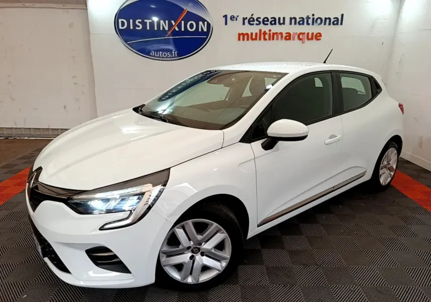 Renault Clio Business TCe 100 blanc en 3/4 avant droit, phares LED allumés, sur sol damier noir et rouge intérieur showroom